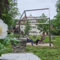 Rahmen eines Hauses ohne Wände und Dach, darunter Menschen auf Stühlen